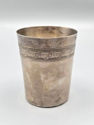 une vieille coupe en argent posée sur une table blanche