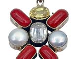 a close up of a flower shaped pendant with red, white and blue stones