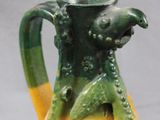 a yellow and green vase with a bird on it