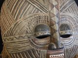 an image of a wooden mask with fringes on a black background