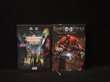 Deux jeux vidéo sont posés sur une surface noire, devant un fond noir.
