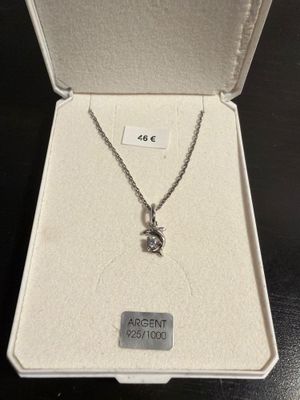 a white box with a silver necklace inside of it on a table