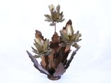 un vase en métal contenant des fleurs, posé sur une surface blanche