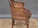 an antique wicker chair with brown leather seat and back