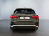 the rear end of a grey car in a room with a white wall