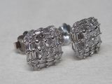 a pair of diamond stud earrings sitting on a table