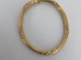 a gold bang bracelet with an intricate design on it