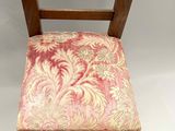 an old wooden chair with a pink and gold upholstered seat