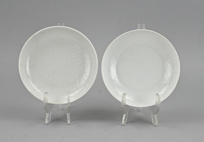 paire d'assiettes en porcelaine blanche sur un socle, sur fond gris