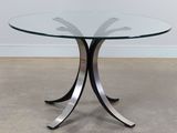 une table en verre avec des pieds en métal et un plateau en verre
