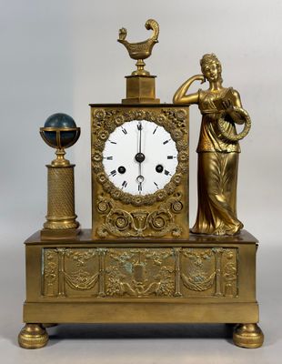 une horloge en or représentant une dame tenant un oiseau et un globe terrestre