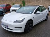 a white tesla model 3 parked in a parking lot