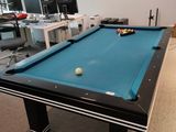 une table de billard avec une boule dessus, dans une pièce