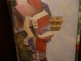 a painting of a house on a easel next to a painting of a house