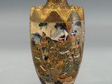 a gold vase with a painting on it on a gray surface