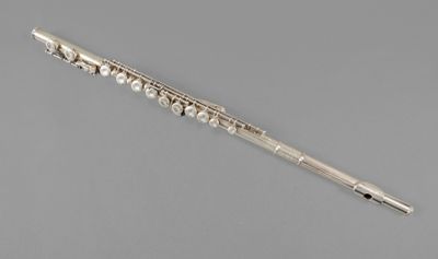 a silver flute with a flute stick on a gray background