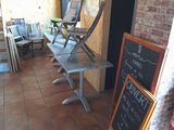 tables and chairs are lined up outside of a restaurant with a chalkboard sign