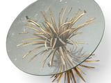 a glass table with a gold plant on it