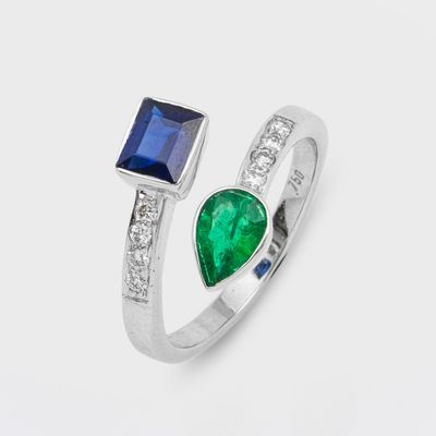 a close up of a ring with two emerald and sapphire stones