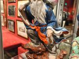 une statue représentant un vieil homme assis sur une table, dans une vitrine
