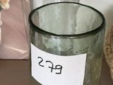 un verre avec une étiquette, posé sur une étagère à côté d'un ours en peluche