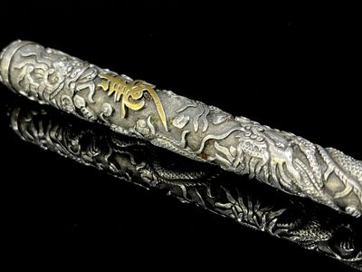 a silver pen with gold writing on it sitting on a black surface
