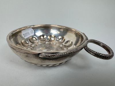 un bol ancien en argent, orné d'une poignée en forme de serpent, posé sur une table blanche
