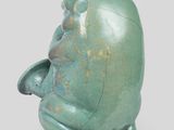 a green statue of a fish that is sitting on a rock