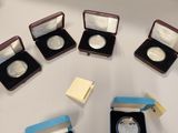 five silver coins in small cases on a table