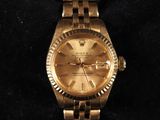 gold rolex watch on a black velvet surface with a black background