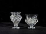 two glass vases sitting on a table with a black background
