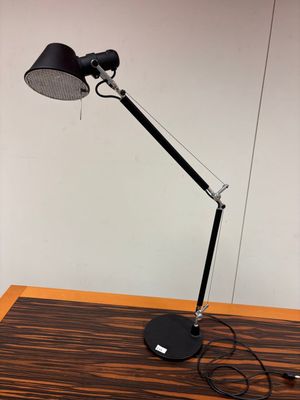 une photo d'une lampe de bureau noire posée sur une table en bois