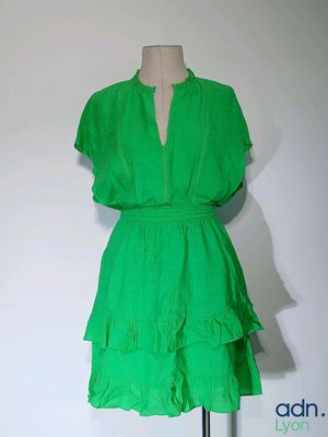une robe verte posée sur un mannequin contre un mur blanc