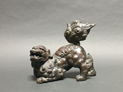 an old bronze statue of a dog on a gray background