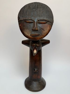 une vieille sculpture en bois représentant un homme coiffé d'un chapeau
