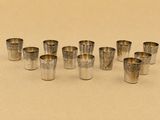 six verres à shot en argent alignés sur une table