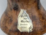 a wooden vase with a metal label on it