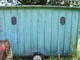 a small blue trailer with two windows in the grass