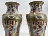 pair of chinese vases with figures painted on them sitting on a white surface