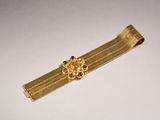 a close up of a gold bracelet with a flower on it