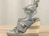 the wedged sandal is made of grey leather and has an open toe