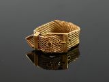 an image of a gold ring with a buckle on a black surface