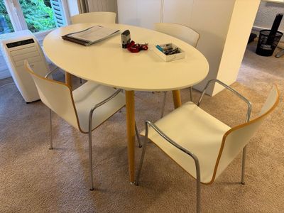 une table blanche avec quatre chaises et un ordinateur portable posé dessus
