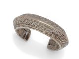 a close up of a silver cuff bracelet on a white background