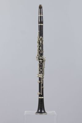 a black and white clarinet on a clear stand against a gray background