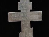 a silver cross on a chain with a black background