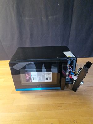 un micro-ondes posé sur une table, la porte ouverte