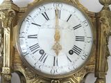 a gold clock with roman numerals on the face