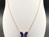a gold necklace with a blue butterfly pendant on a white mannequin