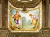 a clock with a painting of two people on it